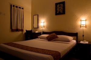 a bedroom with a bed with two lights on the wall at Andrea Hotel in Yogyakarta +9 photos