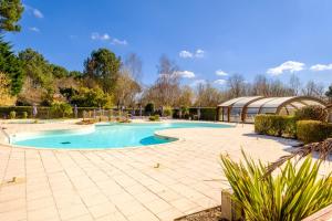 une grande piscine avec une terrasse et un bâtiment dans l'établissement Les Cottages du Lac A05, à Parentis-en-Born