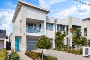 a white house with a blue garage door at Parea on Cavendish - A Perfect Beachside Lifestyle in West Beach