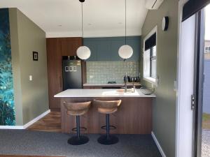 cocina con encimera y 2 taburetes en New two bedroom close to town, en Taupo 5 fotos más