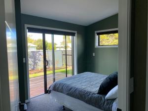 Un dormitorio con una cama y una puerta corrediza de vidrio. en New two bedroom close to town, en Taupo