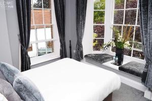 een slaapkamer met een bed en twee ramen bij The Robin Hood Inn in Rowlands Castle +7 foto's