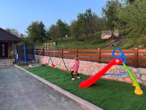 a little girl playing on a swing set at Apartmani Nase brdo in Guča