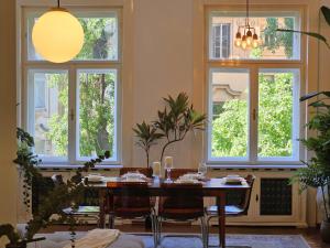 une salle à manger avec une table, des chaises et des fenêtres dans l'établissement Design Old Town Aprt - Blue Church & Park - AC, à Bratislava