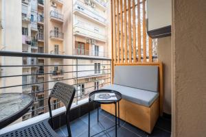 a small balcony with a bench and two tables at City Vibe-Siggrou 44 family in Thessaloniki