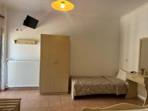 1 dormitorio con 1 cama y armario con TV en Achilleas Apartments, en Paralía Skotínis