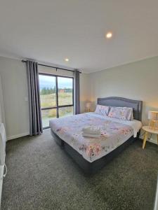 Un dormitorio con una cama y una ventana grande. en April Apartments, en Lake Tekapo