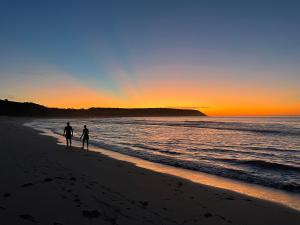 twee mensen lopen op het strand bij zonsondergang bij Coast in Stokes Bay