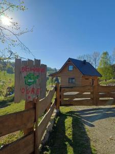 a fence with a sign on it with a house in the background at Dzika Polana in Duszniki Zdrój