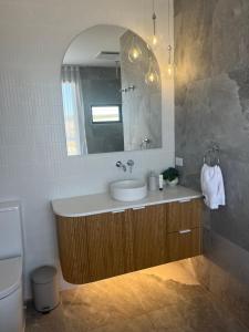 een badkamer met een wastafel en een spiegel bij Coast in Stokes Bay