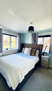 a bedroom with a large white bed with windows at 4 Bedroom home with study space in Horley