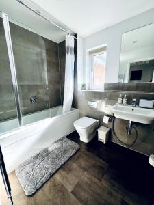 a bathroom with a tub and a toilet and a sink at 4 Bedroom home with study space in Horley +22 photos