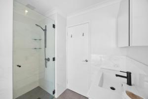 a white bathroom with a shower and a sink at Relaxed Coastal Living with Poolside Bliss - Mullaloo in Perth