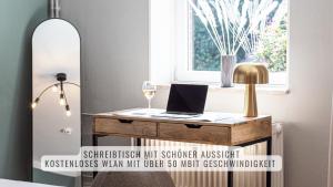 a desk with a laptop and a glass of wine at have-a-nice-Stay - nahe Bahnhof Ahrensburg - 20 Minuten nach Hamburg - trotzdem ruhig gelegen - 6 Minuten zu Fuß ins Zentrum Ahrensburg - modern eingerichtet in Ahrensburg