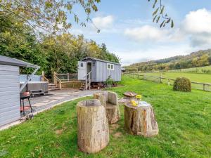 a cabin in a field with logs in the yard at 1 Bed in Hereford 79576 in Aconbury