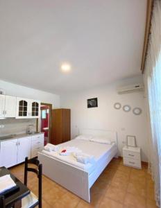 a bedroom with a white bed and a kitchen at Arlind's Apartaments in Vlorë
