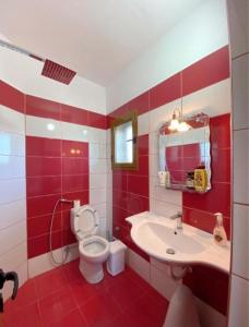 a red and white bathroom with a toilet and a sink at Arlind's Apartaments in Vlorë