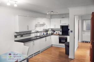 a kitchen with white cabinets and black counter tops at Thistle Apartments - Bon-Accord Apartment in Aberdeen