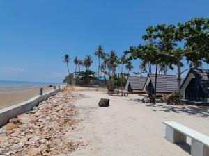 a dog laying on a beach next to houses at หาดกำนันแคมป์ปิ้ง&ซีฟู๊ด in Ban Laem Sui