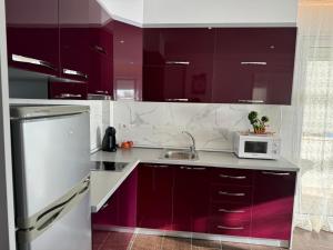 a kitchen with purple cabinets and a microwave at Jonian Waves in Sarandë +3 photos