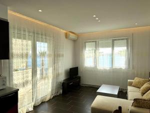 a living room with a couch and two windows at Jonian Waves in Sarandë