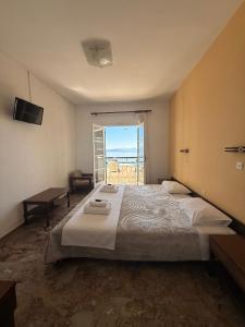 a bedroom with a large bed with a view of the ocean at Nikoli Apartments in Benitses