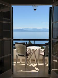 a balcony with a table and chairs and a view of the ocean at Nikoli Apartments in Benitses