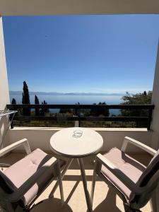 a table and chairs on a balcony with a view of the ocean at Nikoli Apartments in Benitses