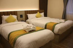 due letti in una camera d'albergo con asciugamani sopra di Sinamangal Airport Hotel a Kathmandu