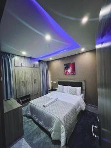 a bedroom with a large bed with a purple lighting at Macdestly Apartment in Abuja