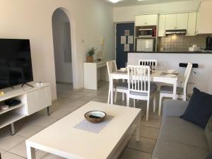 a living room with a couch and a table and a kitchen at Stylish 1BR Apt With Pool - Near Mall, Restaurants & Shops in Paphos