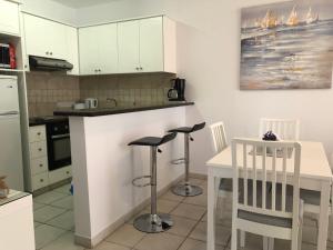 a kitchen with a counter and a table and chairs at Stylish 1BR Apt With Pool - Near Mall, Restaurants & Shops in Paphos