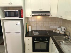 a kitchen with a white refrigerator and a sink at Stylish 1BR Apt With Pool - Near Mall, Restaurants & Shops in Paphos +18 photos