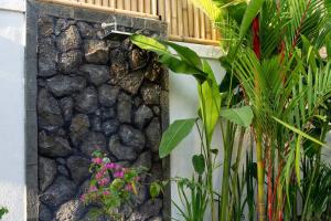 eine Steinmauer mit Pflanzen und einem Springbrunnen in der Unterkunft Stylish 3 BR Villa Near Canggu in Canggu