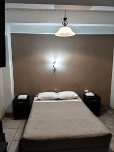 危地马拉Hotel Capri的一间卧室，墙上有一张床和一盏灯