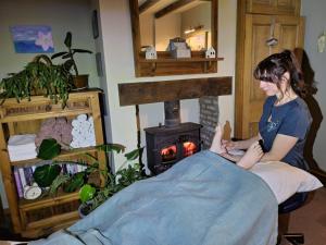 a woman sitting in front of a wood stove at Aldwark Bridge Glamping - Lunar Tent in Aldwark