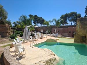 a pool with chairs and umbrellas at a resort at Residence Casale Verderame in Trapani