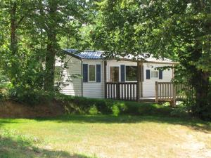 a small white cottage with a porch and trees at Camping la tuque in Belaye +9 photos