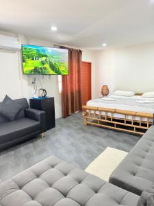 a living room with two beds and a flat screen tv at Harry's Beach Club in Ban Phe