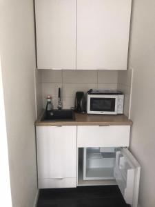 a small kitchen with white cabinets and a microwave at Pokoje do wynajęcia Agnieszka Milewska in Łowicz Wałecki