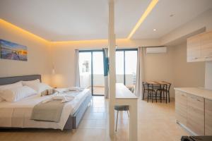 a bedroom with a bed and a kitchen with a table at Blue Wave Suites - Ixia in Ialysos