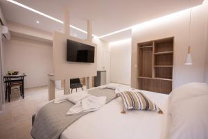 a bedroom with a bed with a tv on the wall at Blue Wave Suites - Ixia in Ialysos