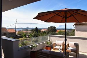 eine Terrasse mit Sonnenschirm und Stühlen auf einem Balkon in der Unterkunft Villa Maksan - Sea View, Jacuzzi & BBQ Garden in Pakoštane