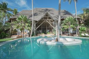 a swimming pool with a resort with palm trees at Boutique Hotel Matlai in Michamvi
