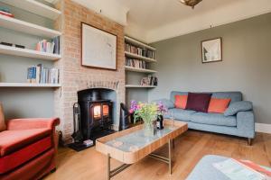 a living room with a couch and a fireplace at Herdsman's Cottage - Beautiful 3 Bed in Wiltshire! in Sherston