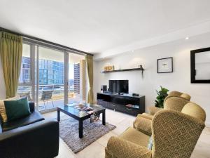 a living room with a couch and a tv and a table at Birds-eye canal view - Walk to CTICC and V&A Waterfront! in Cape Town +10 photos