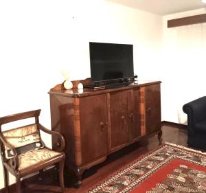 a living room with a tv on a cabinet with a chair at Cleopatrahouse in Stemnitsa