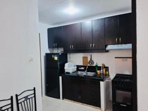 eine Küche mit schwarzen Schränken und einem schwarzen Kühlschrank in der Unterkunft Home in the Historic City Entire House with 3 beds in Lapu Lapu City