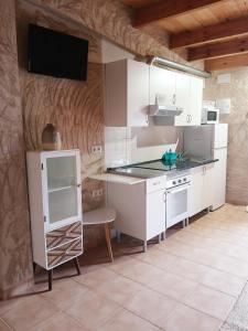 a kitchen with white cabinets and a tv on the wall at Casa Estrella in Villafamés