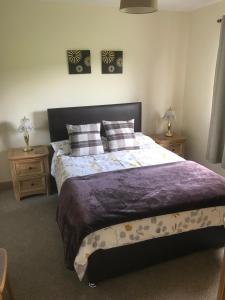 a bedroom with a large bed and two night stands at Ardmore Holiday Cottage in Trumpan